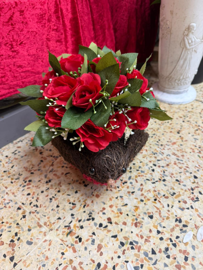 Wicker Robin - A charming wicker robin decoration made from natural woven materials, featuring classic robin detailing and a festive arrangement of red flowers and green foliage.